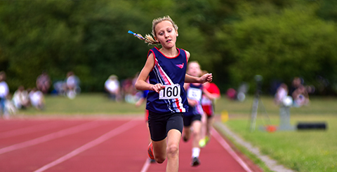 a girl in SSAthletics' garb running on a racetrack