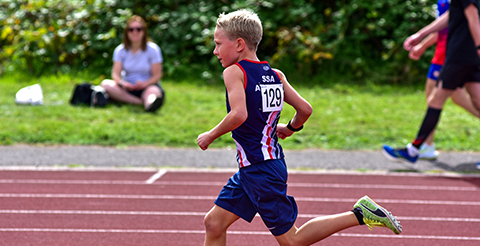 a child in SSAthletics' garb running on a racetrack