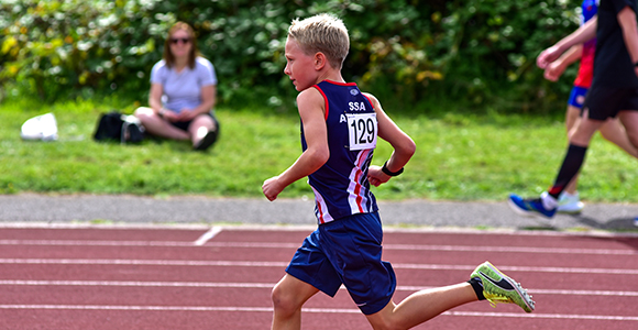 a child in SSAthletics' garb sprinting down a racetrack