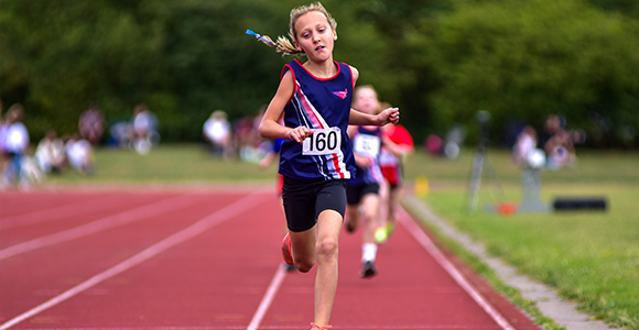 an girl in SSAthletics' garb sprinting down a racetrack