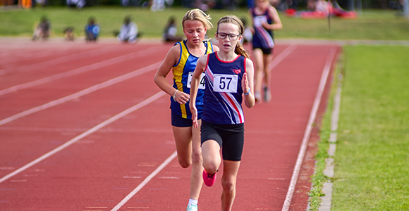 a girl in SSAthletics' garb frontrunning against another competitor in a sprint