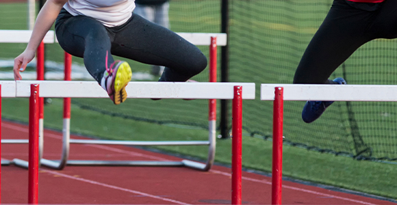 individuals jumping over hurdles on a racetrack
