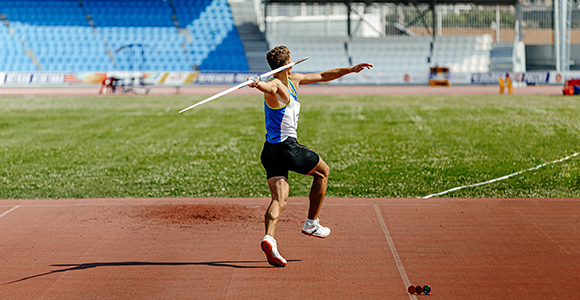 a man preparing to through a javelin across a stadium field